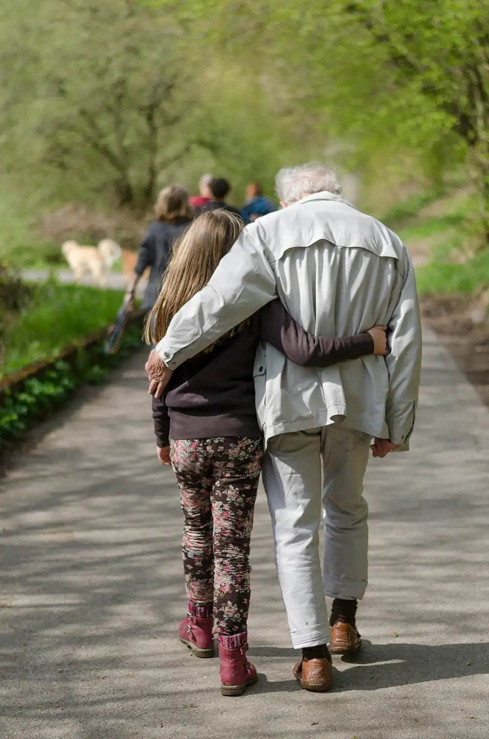 Ältere Person und Kind gehen Arm in Arm spazieren
